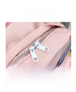 Detail view of smooth double zippers and colorful star patches on pink school backpack