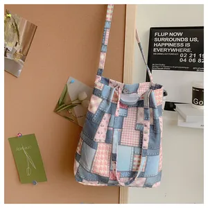 Detail of vintage patchwork canvas tote featuring pink plaid and blue denim fabrics