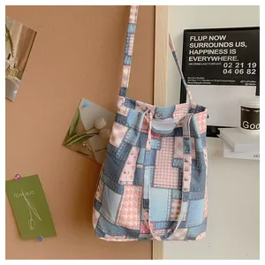 Detail of patchwork denim tote bag with pink plaid accents and silver magnetic buckle