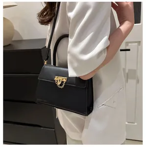 Detailed view of the stylish black crossbody bag with gold lock and chain on a model