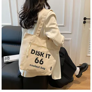 Close-up of cream canvas tote bag with black typography print and front zipper pocket