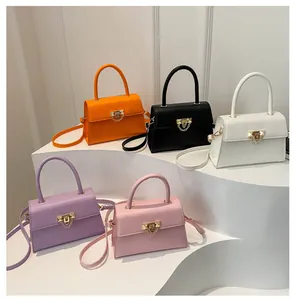 Detail view showing five colors of small square crossbody bags with gold metal clasps