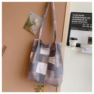 Close-up of a color-block patchwork canvas tote bag hanging on a cork wall background