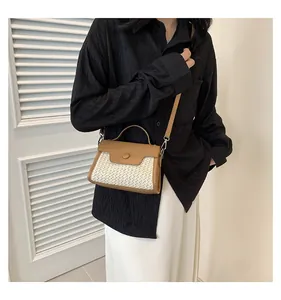 Detailansicht einer Stroh-Minihandtasche mit braunem Lederbesatz und silbernen Metallverschlüssen