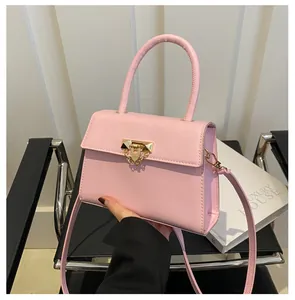 Detailed shot of pink leather square handbag featuring gold hardware and rivet accents