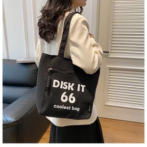Detail of black canvas tote bag showing DISK IT print and side zipper pocket feature