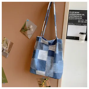 Detail of patchwork denim tote bag with square fabric blocks and reinforced shoulder strap