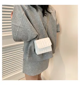 Chic white quilted mini crossbody bag with gold chain strap on grey dress outfit