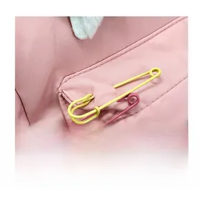 Detail of pink backpack featuring decorative safety pins and soft plush ear accents