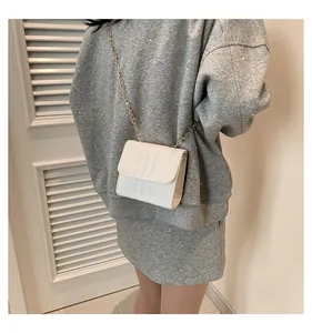 Close-up of stylish cream white chain bag with vertical stitched texture on model