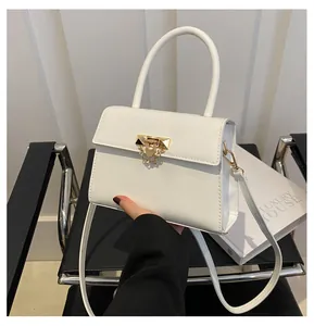 Close-up of white crossbody bag featuring gold geometric metal buckle and smooth PU leather