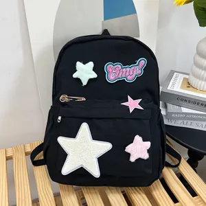 Detail of a black school backpack with embroidered stars and an Omg patch on a wooden bench