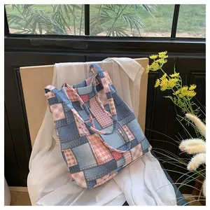 Detail of patchwork denim tote with pink plaid and floral fabric in a cozy indoor setting