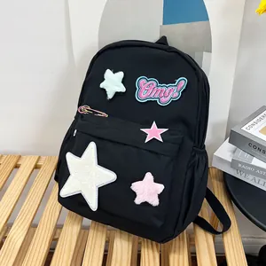 Detail of black canvas backpack featuring colorful plush star patches and Omg embroidery