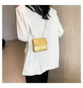 On-body view of a mini gold chain crossbody bag showing compact square design and style