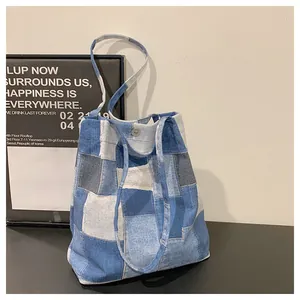 Detailed view of patchwork denim tote bag with blue panels and silver metal buckle