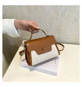 Detailaufnahme der Stroh-Gewebe und braunem Leder Kontrastnähten Tasche auf Buch