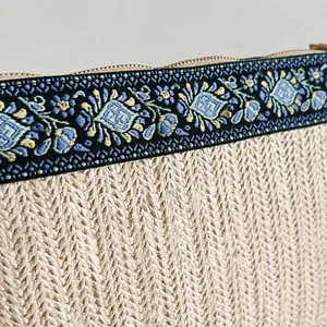 Détail macro de la broderie florale bohème et du tissu en paille avec fermeture éclair