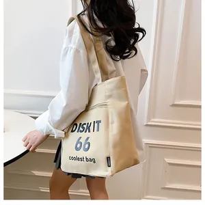Detail of beige canvas tote bag with black typography and zipper for students