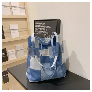 Detail of patchwork denim tote bag with geometric blue blocks and dual shoulder straps