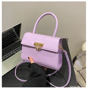 Detail of light purple leather handbag featuring golden lock and circular handle