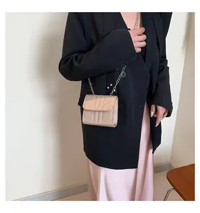 Detail of a champagne quilted chain crossbody bag shown on a model in a smart outfit