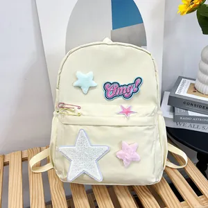 Detail of creamy yellow backpack with star patches, embroidery and decorative pins