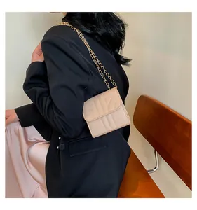 Detail of beige quilted mini crossbody bag with gold chain strap on female model
