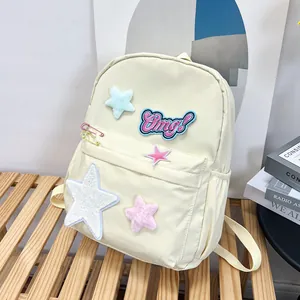 Close-up of off-white nylon backpack with pink Omg embroidery and star charms