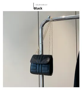 Detail of black quilted mini flap bag with gold chain strap hanging on a silver rack