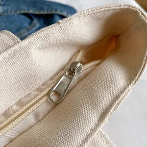 Beige canvas tote bag featuring a high-quality silver metal zipper and durable fabric