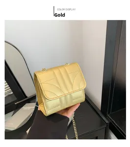 Detail of gold quilted crossbody bag featuring a stylish metal chain strap and flap