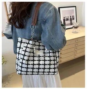 Detail of tweed checkered tote bag with pearl chain decoration and leather straps