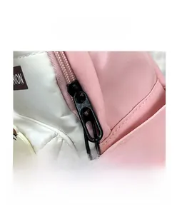 Dettaglio dello zaino rosa e bianco con doppie cerniere metalliche e tasca laterale