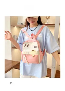 Dettaglio dello zaino patchwork rosa e bianco con un orsetto e un'etichetta di moda