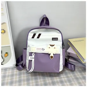 Dettaglio delle tasche e del ciondolo a orsetto sullo zaino viola e bianco