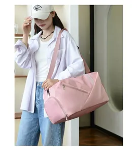 Pink waterproof travel duffel bag with shoulder strap shown in a lifestyle gym setting
