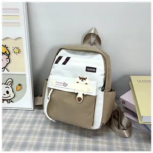 Dettaglio di uno zaino scolastico kaki e bianco con ciondolo animale e logo fashion