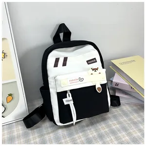 Dettaglio di uno zaino scolastico bianco e nero con tasca frontale e ciondolo orso