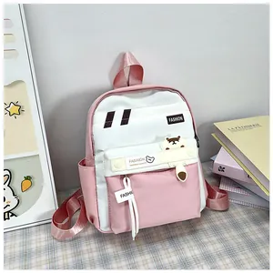 Dettaglio dello zaino scolastico rosa e bianco con etichette fashion e ciondolo orso