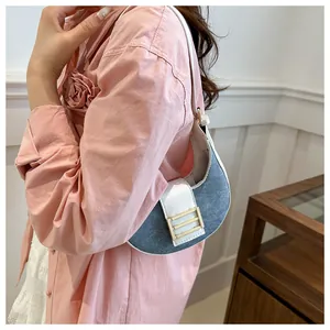 Detalle del bolso de hombro creciente en mezclilla azul y cuero blanco en una modelo