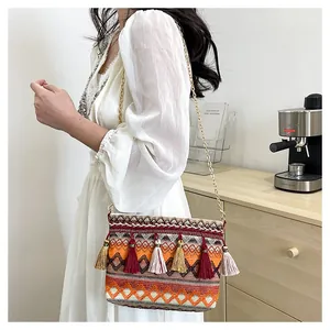 Close-up of bohemian woven shoulder bag featuring colorful tassels and gold chain strap