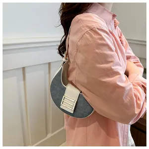 Detalle del bolso de media luna en denim gris con ribete de cuero blanco y hebilla