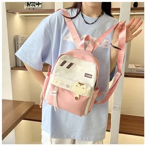 Dettaglio dello zaino scolastico rosa e bianco con ciondolo a forma di orso in libreria