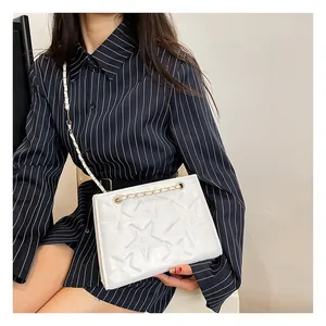 Détail du sac bandoulière blanc à étoiles gaufrées et chaîne dorée sur mannequin