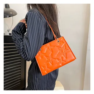 Gros plan d'un sac bandoulière orange vif avec motif étoile en relief et chaîne