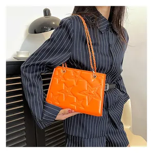 Détail du sac bandoulière orange vif avec étoiles en relief et bandoulière en chaîne