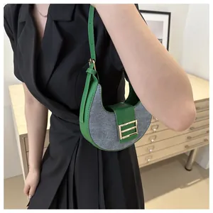 Detalle del bolso de media luna con ribete de cuero verde y cierre de metal dorado