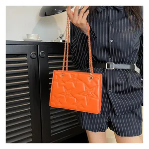 Détail du sac bandoulière orange avec motif d'étoiles gaufrées et bandoulière chaîne dorée