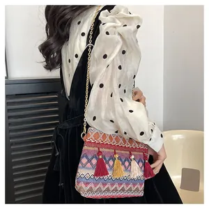 Close-up of bohemian woven shoulder bag with colorful tassels and gold chain strap